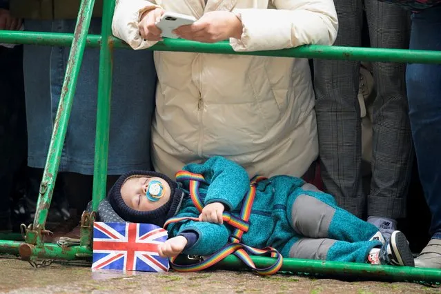 Johann-Maxilian, a 2 and a half year old child, lies on the ground as the members of the public wait for Britain's King Charles to visit the town hall, in Hamburg, Germany on March 31, 2023. (Photo by Fabian Bimmer/Reuters)