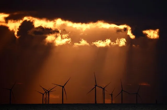 The sun sets behind wind turbines at the Saint-Nazaire offshore wind farm, off the coast of the Guerande peninsula in western France on February 25, 2023. (Photo by Stephane Mahe/Reuters)
