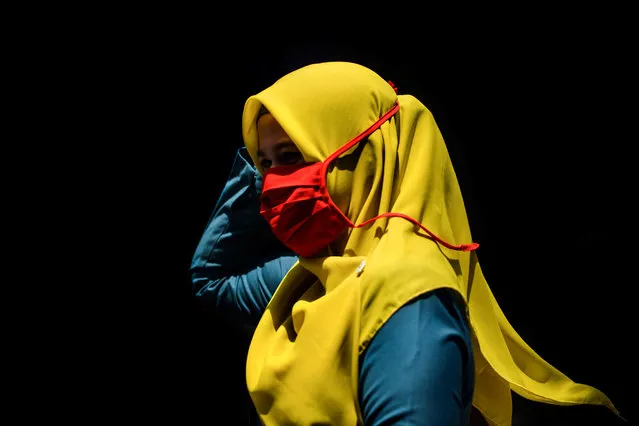 A woman wearing a face mask, as a precautionary measure against the spread of the COVID-19 coronavirus, walks through a market in Banda Aceh on March 24, 2020. (Photo by Chaideer Mahyuddin/AFP Photo)