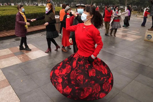 Residents wear masks as they dance at a park in Wuhan in central China's Hubei Province on Saturday, January 23, 2021. A year after it was locked down to contain the spread of coronavirus, the central Chinese city of Wuhan has largely returned to normal, even as China continues to battle outbreaks elsewhere in the country. (Photo by Ng Han Guan/AP Photo)