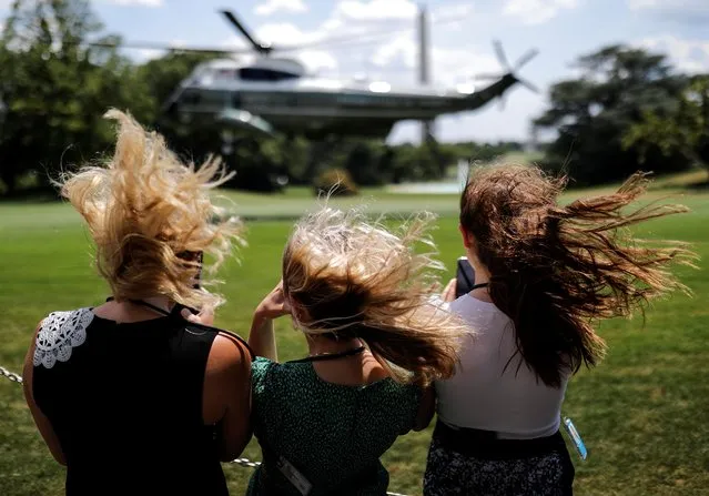 Visitors withstand a strong gust of wind created by Marine One as they watch the helicopter ascend with U.S. President Donald Trump aboard as he departs for travel to Atlanta, Georgia from the South Lawn at the White House in Washington, U.S., July 15, 2020. (Photo by Carlos Barria/Reuters)