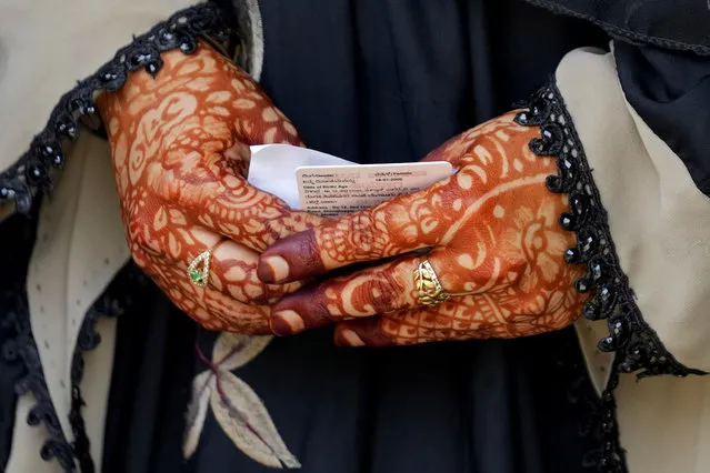 A woman with her hands decorated with henna holds her voter identity card as she waits to cast her vote at a polling station in Bengaluru, India, Wednesday, May 10, 2023. People in the southern Indian state of Karnataka were voting Wednesday in an election where pre-poll surveys showed the opposition Congress party favored over Prime Minister Narendra Modi's governing Hindu nationalist party. (Photo by Aijaz Rahi/AP Photo)