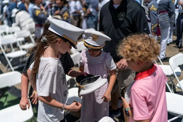 Children look inside one of the hats tossed in the air at the end of the 2023 graduation ceremony at the United States Military Academy (USMA), at Michie Stadium in West Point, New York, U.S., May 27, 2023. (Photo by Eduardo Munoz/Reuters)