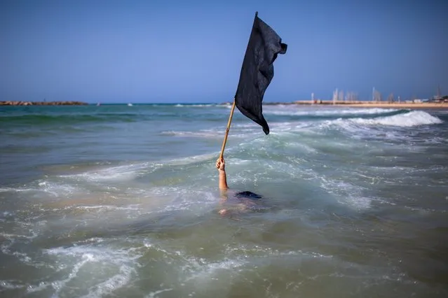 A man waves a black flag in the water during a protest against government's decision to close beaches during the three-week nationwide lockdown due to the coronavirus pandemic,in Tel Aviv, Israel, Saturday, September 19, 2020. Israel went back into a full lockdown on Friday to try to contain a coronavirus outbreak that has steadily worsened for months as its government has been plagued by indecision and infighting. (Photo by Oded Balilty/AP Photo)