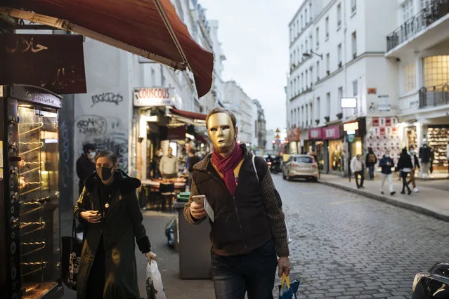 A man wear a golden mask costume walks down a street in Paris, Thursday October 29, 2020. Some doctors expressed relief but business owners despaired as France prepared to shut down again for a month to try to put the brakes on the fast-moving virus. The new measures are set to come into effect at midnight. (Photo by Lewis Joly/AP Photo)