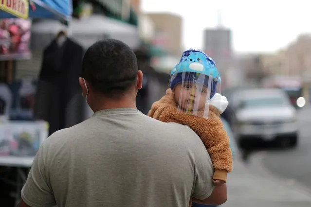 A man carries a baby wearing a mask to protect against the coronavirus disease (COVID-19), in Los Angeles, California, U.S., February 10, 2021. (Photo by Lucy Nicholson/Reuters)