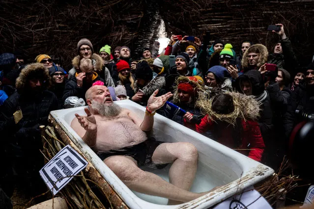 This picture taken on March 13, 2021, shows artist Sergei Pakhomov performing inside a wooden structure “Corona Tower” during celebrations of Maslenitsa, the eastern Slavic Shrovetide in the village of Nikola-Lenivets. Shrovetide or Maslenitsa is an ancient farewell ceremony to winter, traditionally celebrated in Belarus, Russia and Ukraine and involves the burning of a large effigy. (Photo by Dimitar Dilkoff/AFP Photo)