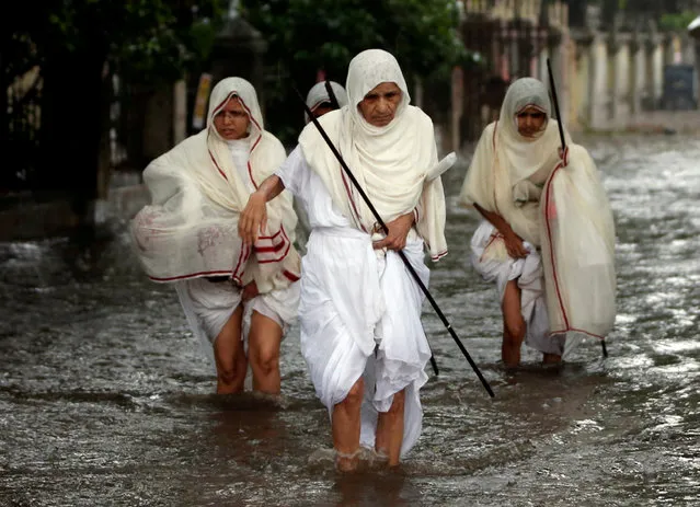 Holy women belonging to the Jain community wade through a waterlogged street after heavy rain in Ahmedabad, India July 20, 2018. (Photo by Amit Dave/Reuters)