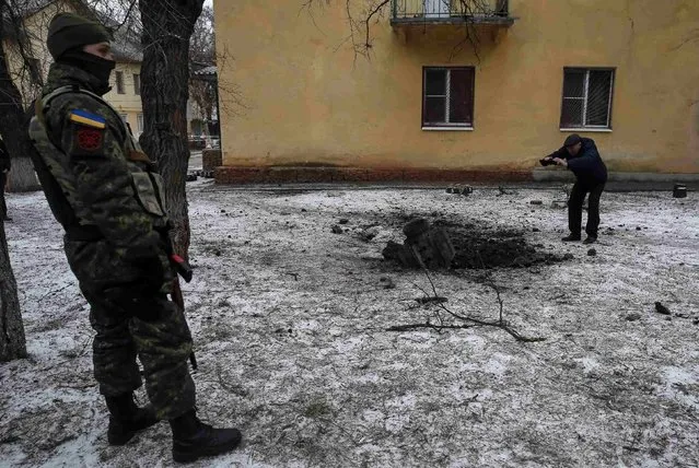 A Ukrainian serviceman guards the street next to the remains of a rocket shell in the town of Kramatorsk, eastern Ukraine February 10, 2015. (Photo by Gleb Garanich/Reuters)