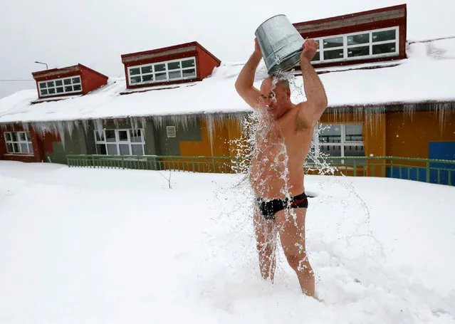 Leonid Gorbunov, 63, a member of a local winter swimmers club, pours a bucket of cold water over himself during a celebration of Polar Bear Day at the Royev Ruchey zoo, with the air temperature at about minus 5 degrees Celsius (23 degrees Fahrenheit), in Krasnoyarsk, Russia, November 27, 2016. (Photo by Ilya Naymushin/Reuters)