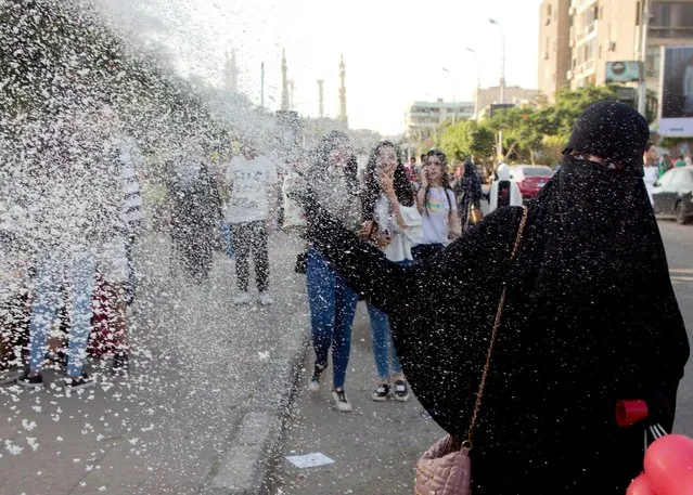 A woman wearing a “Niqab” sprays snow from a can as she joins others celebrating Eid al-Fitr prayers, marking the end of the Muslim holy fasting month of Ramadan outside al-Seddik mosque in Cairo, Egypt, Friday, June 15, 2018. (Photo by Amr Nabil/AP Photo)
