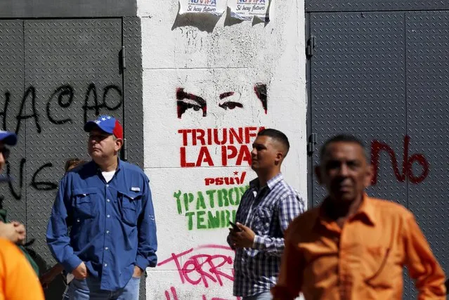 Supporters of Venezuela's President Nicolas Maduro stand in front of a graffiti of the eyes of Venezuela's late President Hugo Chavez some streets away from the building housing the National Assembly in Caracas, January 5, 2016. (Photo by Marco Bello/Reuters)