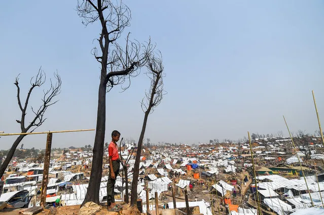A Rohingya refugee child stand at his burnt home days after a fire at a refugee camp in Ukhia, in the southeastern Cox's Bazar district on March 25, 2021. (Photo by Munir Uz Zaman/AFP Photo)
