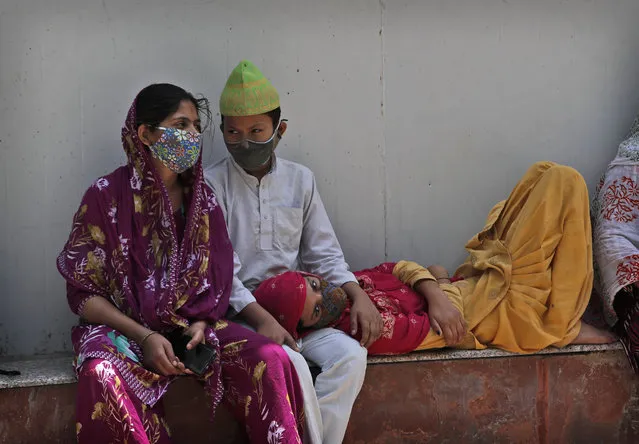 A family waits to receive the body of a person who died due to COVID-19 outside a mortuary, in New Delhi, India, Monday, April 19, 2021. India's health system is collapsing under the worst surge in coronavirus infections that it has seen so far. (Photo by Manish Swarup/AP Photo)