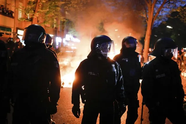 Police officers stand in front of a fire set up by demonstrators during a May Day rally in Berlin, Germany, Saturday, May 1, 2021. (Photo by Markus Schreiber/AP Photo)