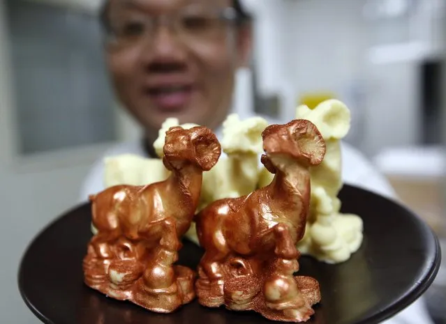 A chef shows goat-shaped chocolates, two of them painted with edible gold powder, as he prepares to make a cake celebrating the upcoming Chinese Lunar New Year, during a photo opportunity at a kitchen of Kerry Hotel in Beijing, February 12, 2015. The price of the cake is 208 RMB ($33), the hotel said. (Photo by Kim Kyung-Hoon/Reuters)