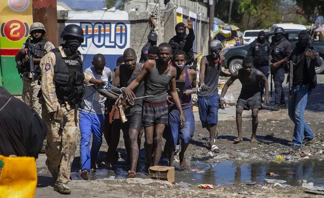 Recaptured inmates are led by police outside the Croix-des-Bouquets Civil Prison after an attempted breakout, in Port-au-Prince, Haiti, Thursday, February 25, 2021. (Photo by Dieu Nalio Chery/AP Photo)