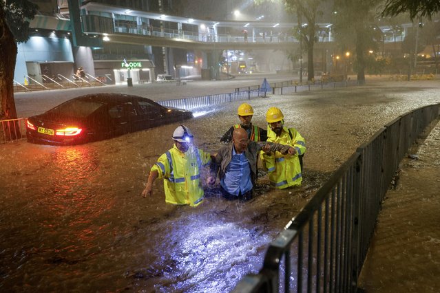 Drainage workers assist a driver stranded due to flooding to a safe place, during heavy rain in Hong Kong, China on September 8, 2023. (Photo by Tyrone Siu/Reuters)