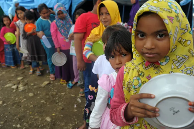 Acehnese displaced people queue for their meal at a shelter after 6.5 Magnitude earthquake in Pidie Jaya, Aceh province on December 12, 2016. Tens of thousands of people have been displaced after a devastating earthquake in Indonesia killed more than 100 people, an official said on December 10, leaving communities in ruins as aid trickled into the disaster-stricken province. (Photo by Chaideer Mahyuddin/AFP Photo)