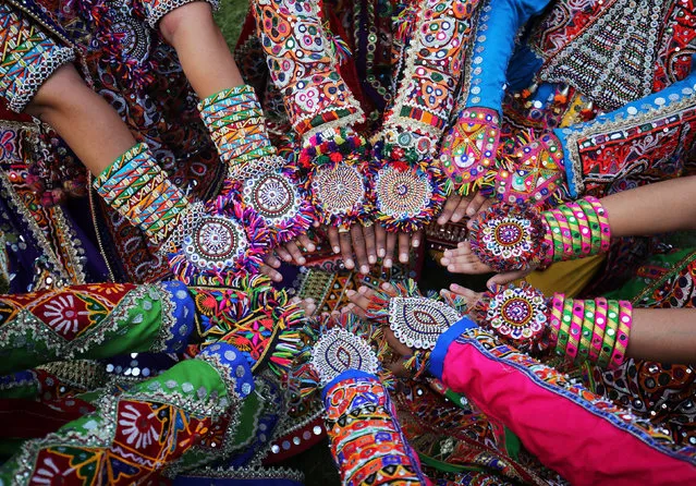 Women dressed in traditional attire display their decorated hands as they pose for pictures during rehearsals for Garba, a folk dance, ahead of Navratri, a festival during which devotees worship the Hindu goddess Durga and youths dance in traditional costumes, in Ahmedabad, India on October 4, 2018. (Photo by Amit Dave/Reuters)