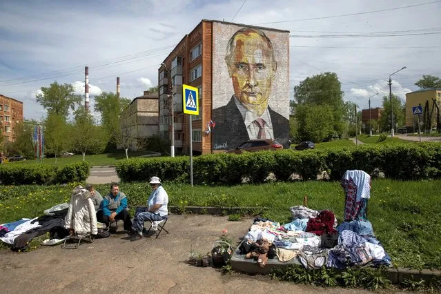 Street vendors sell clothes and flowers near a block of flats with a mural depicting Russian President Vladimir Putin in the town of Kashira in Moscow Region, Russia on May 15, 2021. (Photo by Maxim Shemetov/Reuters)