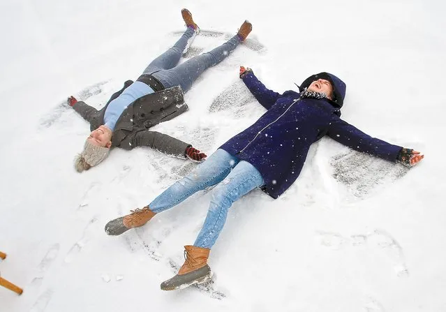 Hannah Harper, left, and Emily Burgess laugh while taking advantage of the fresh snow to make snow angels at Studio 212 Wednesday, January 20, 2016, in Maryville, Tenn., as 1-3 inches of snow was predicted to fall. (Photo by Tom Sherlin/The Daily Times via AP Photo)