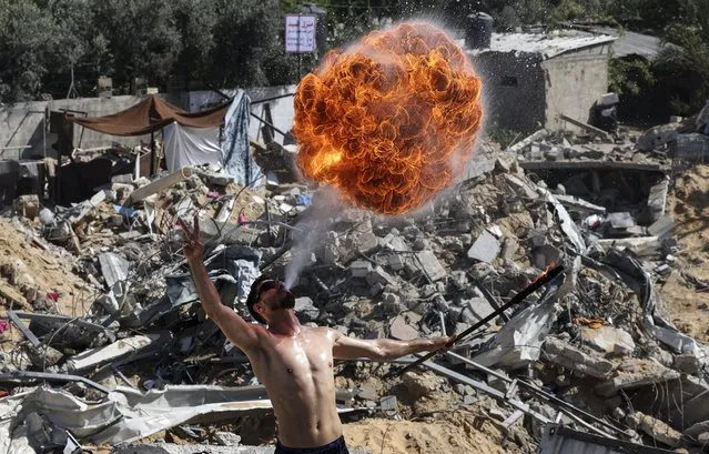Palestinian members of Gaza's Bar Woolf sports team perform with fire above the ruins of a building destroyed in recent Israeli air strikes, in Beit Lahia, on May 26, 2021. A ceasefire was reached late last week after 11 days of deadly violence between Israel and the Hamas movement which runs Gaza, stopping Israel's devastating bombardment on the overcrowded Palestinian coastal enclave which, according to the Gaza health ministry, killed 248 Palestinians, including 66 children, and wounded more than 1,900 people. Meanwhile, rockets from Gaza claimed 12 lives in Israel, including one child and an Israeli soldier. (Photo by Mahmud Hams/AFP Photo)
