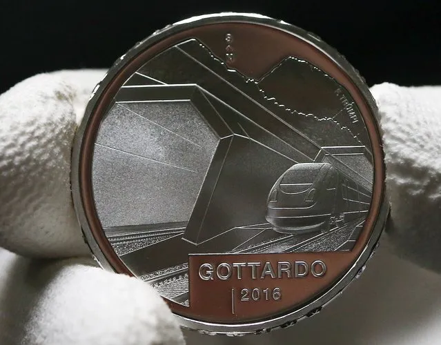An employee shows the front of the silver 20 Swiss Francs Gottardo 2016 official commemorative coin at Swissmint in Bern, Switzerland January 28, 2016. Crossing the Alps, the world's longest train tunnel should become operational at the end of 2016, consisting of two parallel single track tunnels, each of a length of 57 km. (Photo by Ruben Sprich/Reuters)
