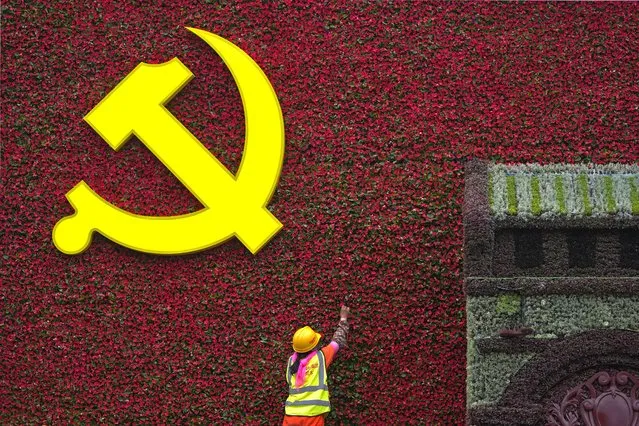 A worker installs a flag-shaped flowers decoration with a Communist Party's logo in Beijing, Wednesday, June 16, 2021. Authorities are gearing up to mark the 100th anniversary of the founding of China's ruling Communist Party, which will be observed on July 1. (Photo by Andy Wong/AP Photo)