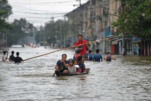 Local residents make their way through a flooded street after heavy rains in Myanmar's Bago region on October 9, 2023. (Photo by Sai Aung Main/AFP Photo)