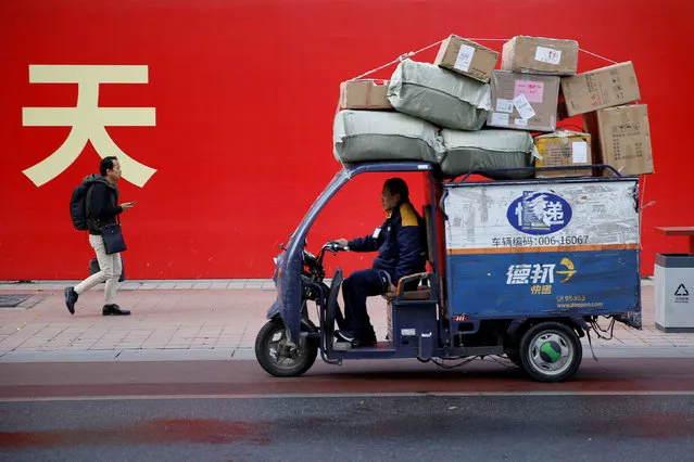 An electric delivery vehicle of Deppon Logistics drives past a banner with a government slogan in Beijing, November 6, 2018. (Photo by Thomas Peter/Reuters)