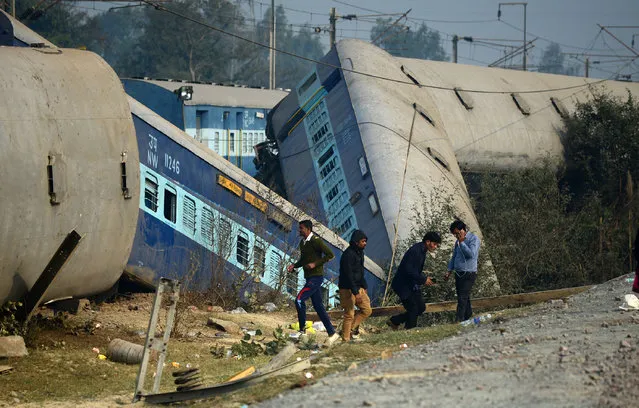 Indian officials and bystanders gather at the derailed train carriages at Rura, some 30 kms west of Kanpur on December 28, 2016, following a train crash in the northern Indian state of Uttar Pradesh. At least two people died and 28 were injured after a train derailed in north India, close to the site of a previous rail accident that killed 146. (Photo by Sanjay Kanojia/AFP Photo)