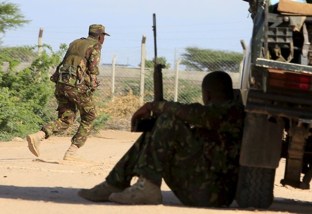 A Kenya Defense Force soldier runs for cover near the perimeter wall where attackers are holding up at a campus in Garissa April 2, 2015. At least 14 people were killed on Thursday when Islamist militant group al Shabaab stormed the Kenyan university campus, taking Christians hostage and engaging security forces in a shootout for several hours. (Photo by Noor Khamis/Reuters)
