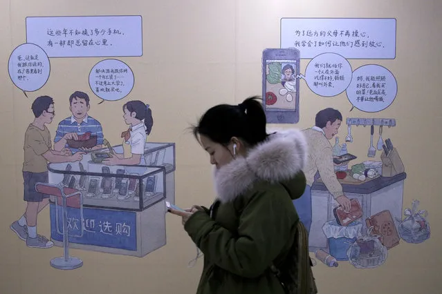 A woman browses her iPhone as she walks by a mural depicting an iPhone and Chinese people buy smartphone to communicate with family members, at a subway station in Beijing, Thursday, January 3, 2019. Apple Inc.’s $1,000 iPhone is a tough sell to Chinese consumers who are jittery over an economic slump and a trade war with Washington. The tech giant became the latest global company to collide with Chinese consumer anxiety when CEO Tim Cook said iPhone demand is waning, due mostly to China. Weak consumer demand in the world’s second-largest economy is a blow to industries from autos to designer clothing that are counting on China to drive revenue growth. (Photo by Andy Wong/AP Photo)