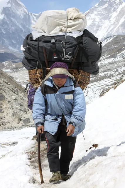 A porter walks along a trail carrying a load belonging to trekkers returning from Everest Base Camp, at Thuglha Pass, Nepal, Friday, April 10, 2015. According to reports in the state run China Daily, a proposed plan for a rail link from China to Nepal could involve boring a tunnel under the 8,850-meter (29,035-foot) Mount Everest. The building of a rail link from Chinese-controlled Tibet to Nepal would need to pass beneath the Himalayan mountain range, according to reports. (Photo by Tashi Sherpa/AP Photo)