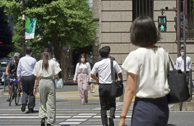 People wearing face masks to help curb the spread of the coronavirus cross an intersection in Tokyo Thursday, August 5, 2021. Tokyo reported 5,042 new daily coronavirus cases on Thursday, hitting a record since the pandemic began as the infections surge in the Japanese capital hosting the Olympics. (Photo by Kantaro Komiya/AP Photo)