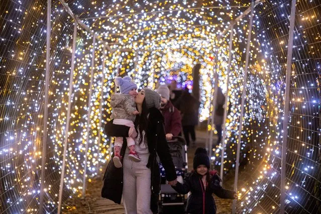 A woman kisses a child on an estate owned by the Salaj family which is lit with 5 million Christmas lights in Grabovnica, Croatia on December 17, 2023. (Photo by Antonio Bronic/Reuters)