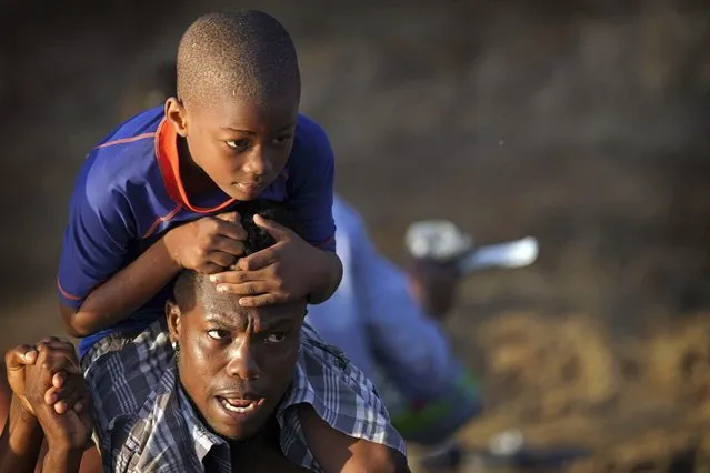 A man carries a boy across the Rio Grande river as migrants, many from Haiti, leave Del Rio, Texas to return to Ciudad Acuna, Mexico, early Wednesday, September 22, 2021, some to avoid possible deportation from the U.S. and others to load up on supplies. (Photo by Fernando Llano/AP Photo)