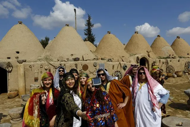 Tourists wearing local costumes pose for a selfie with beehive houses in the background in Harran, a major ancient city of Upper Mesopotamia, Turkey February 28, 2016. (Photo by Murad Sezer/Reuters)