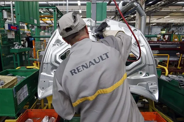 An employee works on the automobile assembly line of a Renault Clio IV at the Renault automobile factory in Flins, west of Paris, France, May 5, 2015. (Photo by Benoit Tessier/Reuters)
