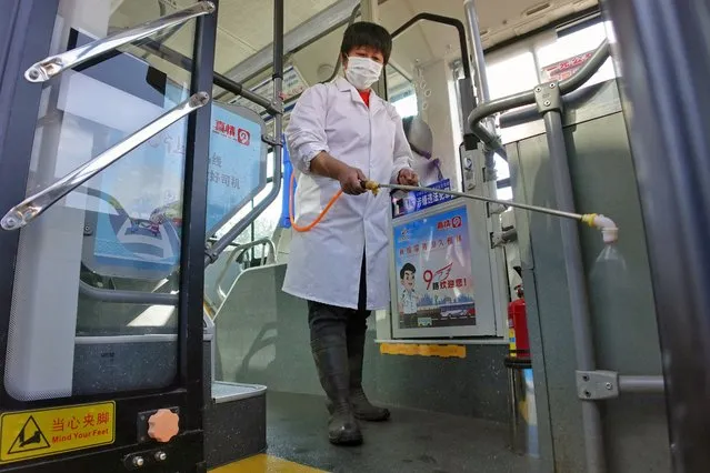 A staff member sprays disinfectant on a bus as a preventive measure against the Covid-19 coronavirus, in Yantai in China's eastern Shandong province on October 28, 2021. (Photo by AFP Photo/China Stringer Network)
