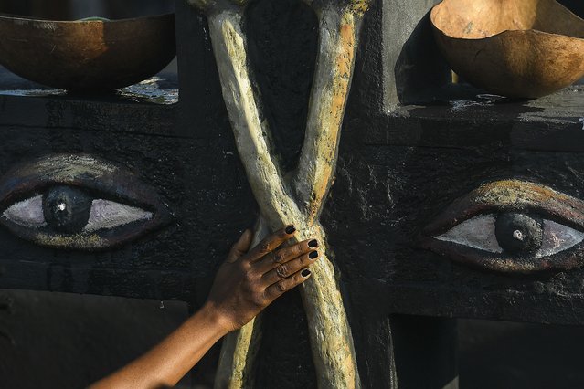 A person touches a monument to Baron Samedi and Gede during a ceremony honoring the Haitian Vodou spirit at the National Cemetery in Port-au-Prince, Haiti, Monday, November 1, 2021. (Photo by Matias Delacroix/AP Photo)
