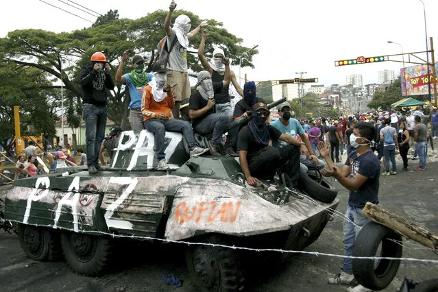 Opposition supporters stand over a monument of a tank which they dragged into the middle of the street during a protest against Nicolas Maduro's government in San Cristobal, some 410 miles (660 km) southwest of Caracas February 19, 2014. Tensions have risen in Venezuela since Lopez, a 42-year-old Harvard-educated economist, surrendered to troops on Tuesday after spearheading three weeks of often rowdy demonstrations against President Nicolas Maduro's government. (Photo by Carlos Eduardo Ramirez/Reuters)