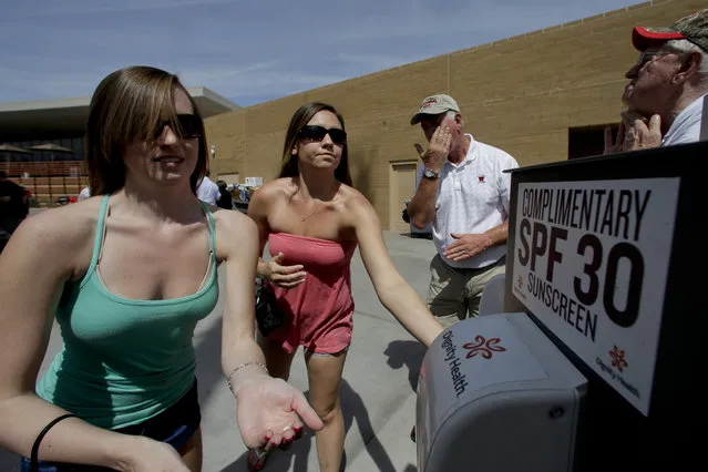 Ashleigh Vincent, left, and Tara Gregory rub out a sunscreen on the first day of spring before a spring exhibition baseball game between the Colorado Rockies and the Milwaukee Brewers in Scottsdale, Ariz., Thursday, March 20, 2014. (Photo by Chris Carlson/AP Photo)