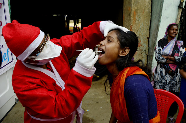 A medical worker dressed in a Santa Claus takes a swab test amid Omicron coronavirus emergency in Kolkata, India, 24 December, 2021. (Photo by Indranil Aditya/NurPhoto via Getty Images)