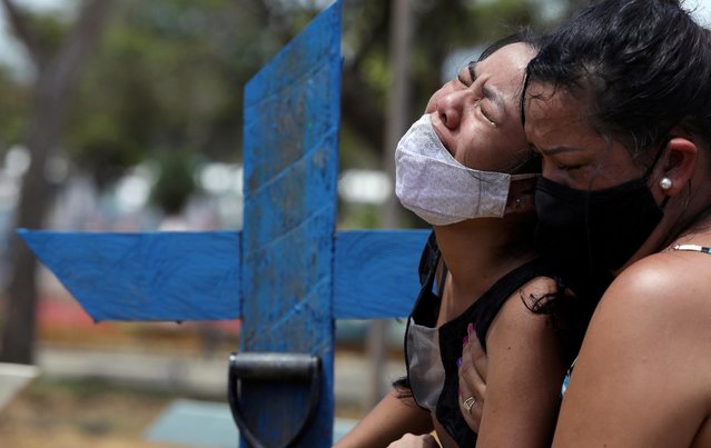 Kelvia Andrea Goncalves, 16, is supported by her aunt Vanderleia dos Reis Brasao, 37, as she reacts during the burial of her mother Andrea dos Reis Brasao, 39, who passed away due to the coronavirus at Delphina Aziz hospital, at the Parque Taruma cemetery in Manaus, Brazil, January 17, 2021. (Photo by Bruno Kelly/Reuters)