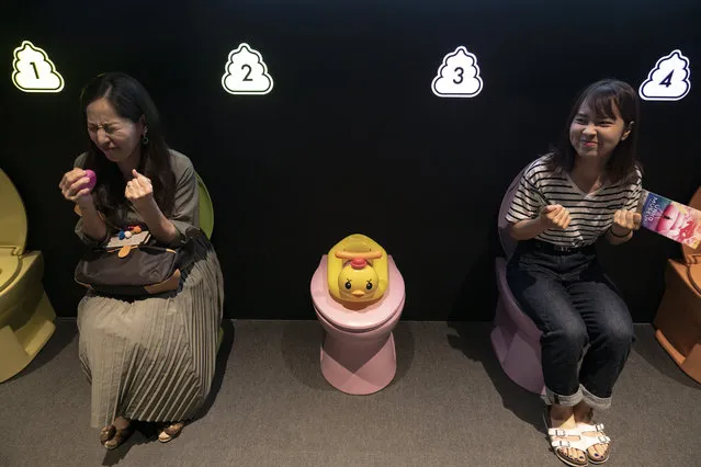In this Tuesday, June 18, 2019, photo, two women jokingly motion to give a push while sitting on colorful toilet bowls at the Unko Museum in Yokohama, south of Tokyo. In a country known for its cult of cute, even poop is not an exception. A pop-up exhibition at the Unko Museum in the port city of Yokohama is all about unko, a Japanese word for poop. The poop installations there get their cutest makeovers. They come in the shape of soft cream, or cupcake toppings. (Photo by Jae C. Hong/AP Photo)