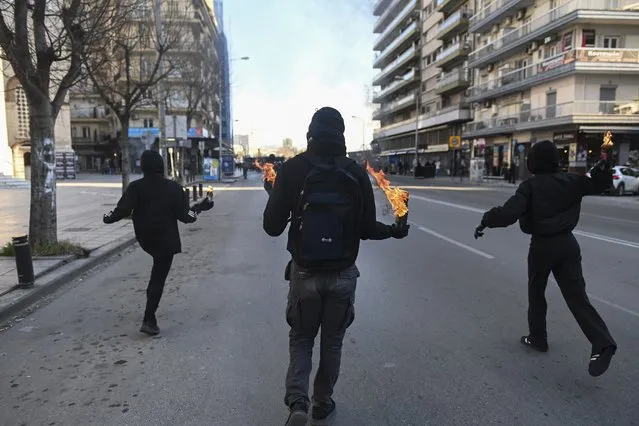 Protesters throw petrol bombs toward policemen during a rally in the northern Greek city of Thessaloniki, Greece, on Saturday, January 15, 2022. The rally was the culmination of a week of protests over the New Year's Eve eviction of activists who had occupied a room at the university's Biology department for 34 years and turned violent towards its end, when some of the marchers threw firebombs and rocks at riot police, who responded with stun grenades and tear gas. (Photo by Giannis Papanikos/AP Photo)