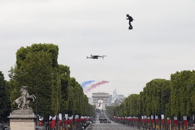 Zapata CEO Franky Zapata flies a jet-powered hoverboard or “Flyboard” as French elite acrobatic flying team “Patrouille de France” (PAF) flies over the Arc de Triomphe during the Bastille Day military parade down the Champs-Elysees avenue in Paris on July 14, 2019. (Photo by Lionel Bonaventure/AFP Photo)