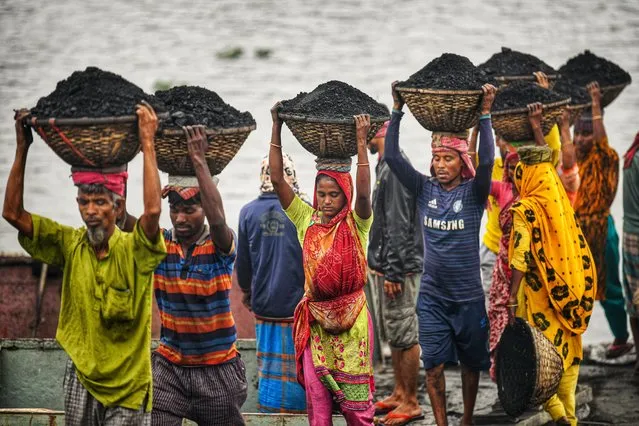 Bangladeshi day labourers carry baskets of coal from a cargo ship in Gabtoli, Dhaka on January 2, 2022. They are earning around $1 every 30 baskets of coal unloaded from the ship. (Photo by Piyas Biswas/SOPA Images/Rex Features/Shutterstock)